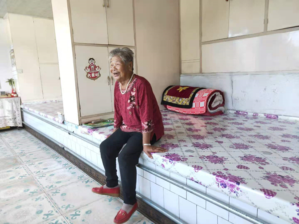 83岁的邱凤琴老人坐在炕上露出了幸福的笑容